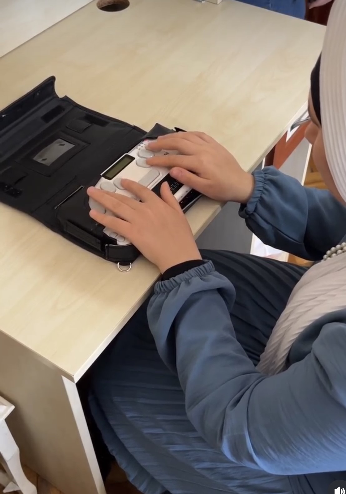 A student using a braille keyboard to type up her lesson